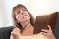 Thoughtful woman holding her glasses and reading a book Royalty Free Stock Photo