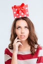 Thoughtful woman looking up at gift box on head Royalty Free Stock Photo