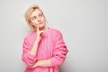 Thoughtful woman looking upwards, hand on chin, contemplating, on a light grey background Royalty Free Stock Photo