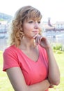 Thoughtful woman in a pink shirt outside