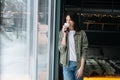 Thoughtful woman standing in a bedroom next to a window, drinking coffee