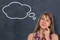 Thoughtful woman with thought bubble on blackboard