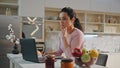 Thoughtful woman working laptop sitting kitchen close up. Girl making notes. Royalty Free Stock Photo