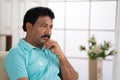 Thoughtful worried indian middled aged man deep thinking while sitting on sofa at home - concept of loneliness Royalty Free Stock Photo