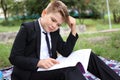 Boy in a suit reads a book in nature