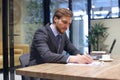 Thoughtful young business man writing something down while working in modern office Royalty Free Stock Photo