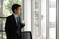 Thoughtful young businessman drinking coffee, looking through window, having break, deep in thoughts, enjoying view Royalty Free Stock Photo