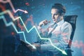 Thoughtful young businessman sitting with laptop and falling forex chart arrows on blurry office interior background. Financial