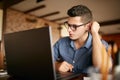 Thoughtful young caucasian businessman in glasses working on laptop computer. Pensive attractive hipster freelancer Royalty Free Stock Photo