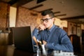 Thoughtful young caucasian businessman in glasses working on laptop computer. Pensive attractive hipster freelancer Royalty Free Stock Photo