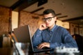 Thoughtful young caucasian businessman in glasses working on laptop computer. Pensive attractive hipster freelancer Royalty Free Stock Photo