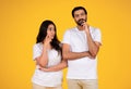 Pensive couple in thought, standing against a yellow background Royalty Free Stock Photo