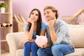 Thoughtful young couple with piggy bank at home