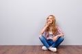 Thoughtful young cute smiling woman sitting on the floor and thi Royalty Free Stock Photo