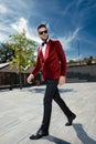 Thoughtful young elegant man walking in red velvet tuxedo Royalty Free Stock Photo