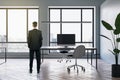 Thoughtful young european business man standing in modern meeting room office interior with wooden flooring, furniture, computers Royalty Free Stock Photo