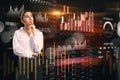 Thoughtful young european business woman with creative global forex chart on dark background. Concept of stock market and