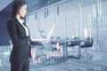 Thoughtful young european businesswoman with laptop standing on blurry office interior background with creative glowing big data Royalty Free Stock Photo