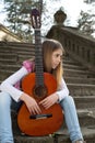 Thoughtful Young Girl With Guitar Sitting on the Stairs and Looking Away Royalty Free Stock Photo