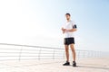 Thoughtful young handsome sportsman standing on the beach pier Royalty Free Stock Photo