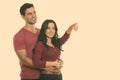 Thoughtful young happy couple smiling while hugging each other with woman pointing at distance Royalty Free Stock Photo