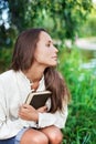 Thoughtful Young lady with book near the river Royalty Free Stock Photo