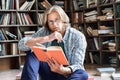 Thoughtful young male student glasses read book library floor education concept Royalty Free Stock Photo