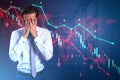 Thoughtful young man with covered face and falling red forex chart and map on dark blurry office background. Trade and crisis Royalty Free Stock Photo