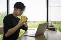 Thoughtful man entrepreneur drinking hot coffee and reading news on laptop computer. Royalty Free Stock Photo