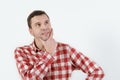 Thoughtful young man in hipster shirt holding hand on chin and standing against white background Royalty Free Stock Photo