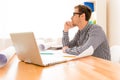 Thoughtful young man holding hand on chin and looking away while sitting at his working place Royalty Free Stock Photo