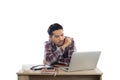 Thoughtful young man holding pen looking at notepad while sitting at his working place. Royalty Free Stock Photo