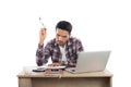 Thoughtful young man holding pen looking at notepad while sitting at his working place. Royalty Free Stock Photo