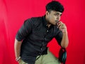 Thoughtful young man posing against a red background with a pensive expression dressed in a checkered shirt Royalty Free Stock Photo