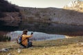 Young man studying map on modern digital tablet on nature while sitting near lake Royalty Free Stock Photo