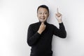 A thoughtful young man wearing a black shirt while looking and pointing at copy space above him, isolated by white background Royalty Free Stock Photo