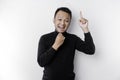 A thoughtful young man wearing a black shirt while looking and pointing at copy space above him, isolated by white background Royalty Free Stock Photo