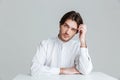 Thoughtful young man in white shirt sitting at the table Royalty Free Stock Photo