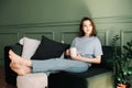 A thoughtful young middle-aged woman enjoying a rest and a cup of tea on the couch, pondering, looking at the open space Royalty Free Stock Photo