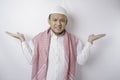 A thoughtful young Muslim man shrugging his shoulders, gesturing confusion isolated by white background