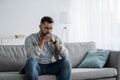 Thoughtful young serious handsome man sit on sofa at home, lost in thoughts, thinking about problem solving Royalty Free Stock Photo