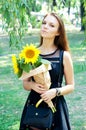 Thoughtful young woman in black dress holding sunflowers Royalty Free Stock Photo