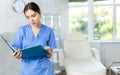 Young woman doctor standing in doctor's cabinet with document in hands Royalty Free Stock Photo