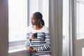 What are the neighbours up to now. A thoughtful young woman gazing out of a window on her coffee break. Royalty Free Stock Photo