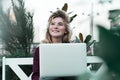 Thoughtful young woman in glasses using a computer, sitting on a bench in a city park. The concept of time is online and work in