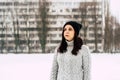 Thoughtful young woman in gray knitted sweater and hat standing on street in winter season. Pretty brunette looking away Royalty Free Stock Photo