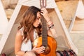 Thoughtful young woman with guitar in teepee on the beach Royalty Free Stock Photo