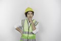 A thoughtful young woman labor worker wearing safety helmet and vest is looking aside to an idea on copy space..
