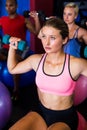 Thoughtful young woman lifting dumbbell in gym Royalty Free Stock Photo