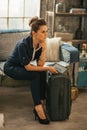 Thoughtful young woman with luggage and tablet pc